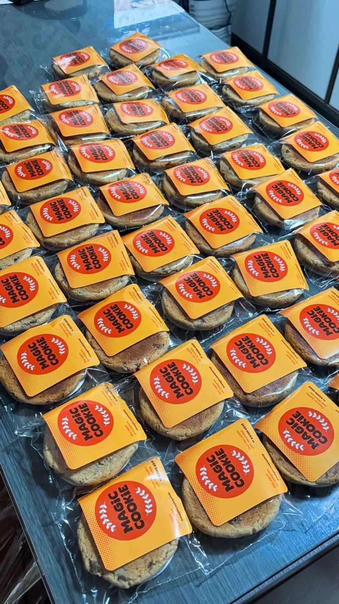 Dezenas de cookies embalados um a um, cada um com o selo laranja da Magic Cookie
